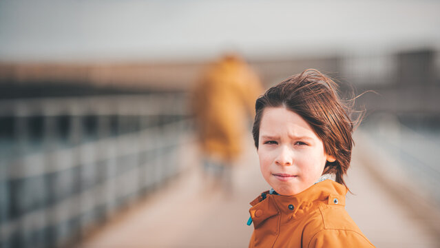 Pensive Boy in Mustard Rain Jacket, Windblown Hair, Copy Space