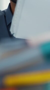 Closeup overworked young Latin businessman reading document in large stack of paperwork file at office desk. Tax audit deadline, accounting stress, corporate burnout, bookkeeping, bureaucracy concept.