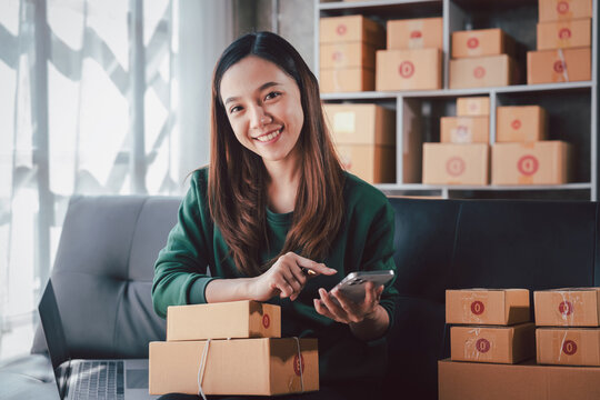 Asian Young Woman Managing Online Business with Mobile Phone at