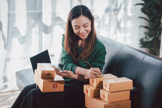Asian Woman Small Business Owner Packing Boxes for Shipping at H