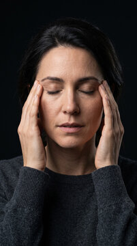 Retrato comercial de alta resoluci&oacute;n enfocado estrechamente en un adulto experimentando fatiga visual digital significativa, masajeando suavemente sus sienes