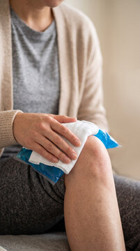 Retrato comercial de alta resoluci&oacute;n de un adulto en ropa de descanso c&oacute;moda sentado en el interior, aplicando una bolsa de hielo en gel sobre una rodilla hinchada