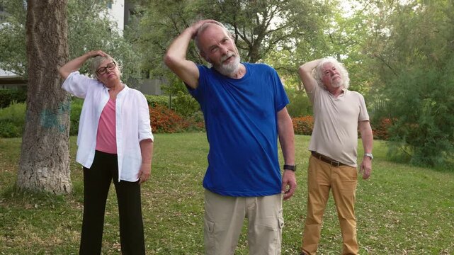 Elderly people doing stretching and wellness exercises in a city park together