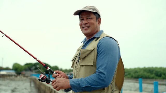 Portrait Senior man preparing fishing gear by the seaside. Retirement lifestyle active aging. Healthy longevity, outdoor recreation, peaceful leisure. Life insurance planning for a secure retirement.
