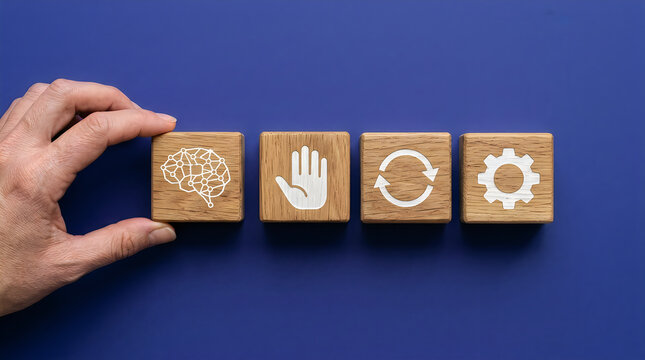 Human hand arranges four wooden blocks featuring brain, hand, refresh, and gear icons for strategic business development and creative conceptual planning