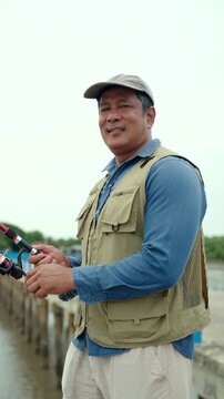Portrait Senior man preparing fishing gear by the seaside. Retirement lifestyle active aging. Healthy longevity, outdoor recreation, peaceful leisure. Life insurance planning for a secure retirement.
