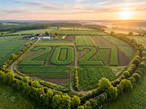 Aerial view of farmland with 2027 shaped crop formation at sunrise