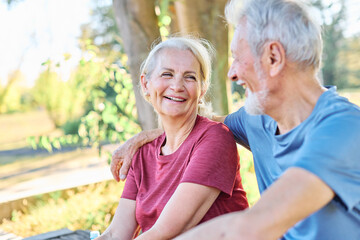 Obraz na płótnie Canvas Happy active senior couple having fun talking holding hands and bonding after having an exercise in park outdoors