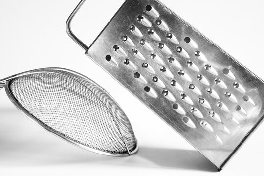 kitchen grater  and a strainer on white background, kitchen utensils,cutlery,food and drink concept, black and white image.