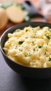 Bowl of creamy mashed potatoes rotating on wooden table