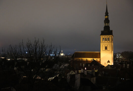 St. Nicholas Church at night in Tallinn, illuminated Gothic church tower above the rooftops of Tallinn Old Town 