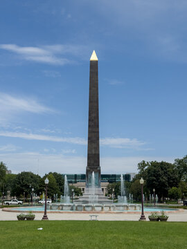 View of the Indiana World War Memorial obelisk with its golden cap, surrounded by a fountain and manicured green lawns in Indianapolis, Indiana, United States.