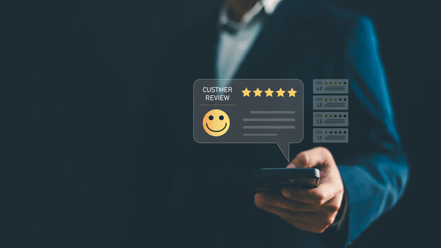 Businessman holding smartphone with customer review star rating and happy face icon concept. Excellent service evaluation, customer satisfaction, feedback experience, and business reputation