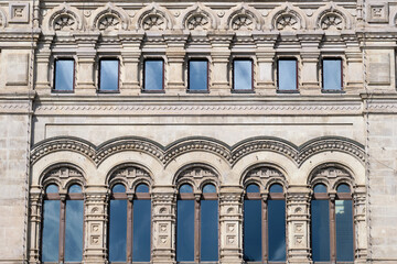 Fototapeta premium Ornate historic building facade with symmetrical arched windows and classical architectural detail. Urban heritage background for architecture, restoration, and cultural history.
