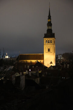 illuminated St. Nicholas Church towering over the historic old town buildings at night
