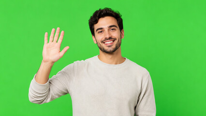 Naklejka premium A smiling young man waves hello against a vibrant green background, exuding friendliness and approachability.