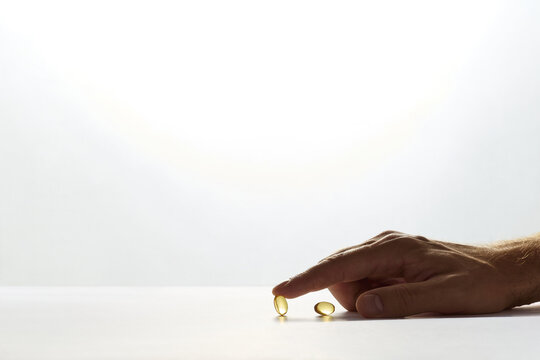 Male Hand Touching Omega-3 Fish Oil Capsule on White Surface with Copy Space