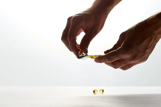 Hands taking yellow vitamin oil capsule from blister pack
