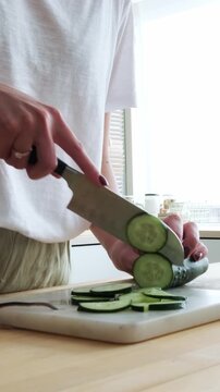 Woman's hands slicing fresh green cucumber