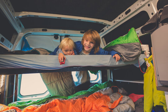 Children, having fun in camper van while heavy raining outdoors, playing and making mischiefs