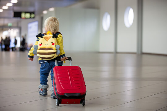 Cute  baby boy waiting boarding to flight in airport transit hall near departure gate. Active family lifestyle travel by air with child