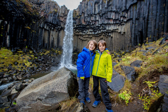 Happy child, posing in front of beautiful waterfall Svartifoss in Skaftafell national park