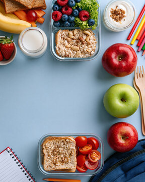 School lunch box blank space apple fruit sandwich berry yogurt milk notebook pencil with healthy meal on blue background for student snack flat lay
