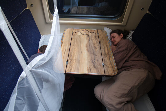 Woman and child sleeping in train compartment. Family resting during long distance rail travel. Comfortable passenger cabin on night journey. Transportation, tourism and adventure concept.