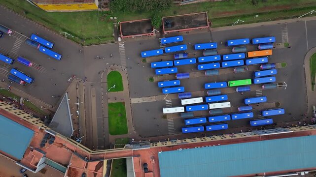 Aerial view of the busy bus station in Kigali with rows of parked blue buses and commuters walking between vehicles in Kigali, Kigali City, Rwanda.