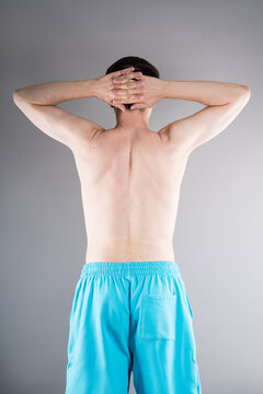 Unrecognizable man shirtless performs exercises for muscles of upper back, arms and shoulder joint. Posture correction and physical therapy