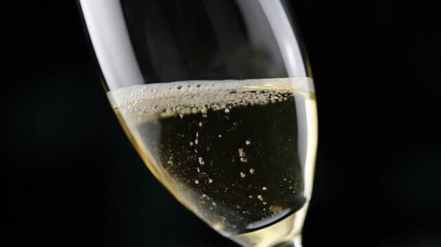 Extreme close-up of champagne bubbles rising intensely in a luxury flute glass on a black background, showcasing detail and celebration.