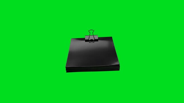 A stack of black paper sheets held together by a metal binder clip on green