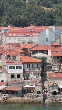 Vertical 9:16 video showing the picturesque waterfront of Combarro, Galicia, Spain. The background includes lush green trees and more modern residential buildings.