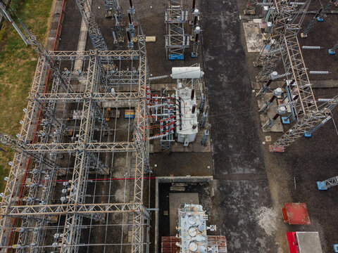 Aerial view of an electrical substation featuring large transformers, complex steel support structures, and power lines in Purwokerto Selatan, Central Java, Indonesia.