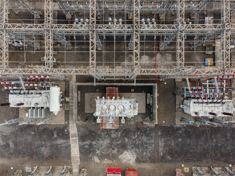 Aerial view of an electrical substation featuring large power transformers, intricate metal framework, and high-voltage equipment in Purwokerto Selatan, Central Java, Indonesia.
