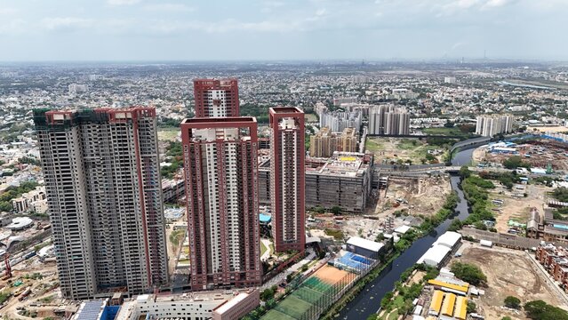 Aerial view of SPR CITY Highliving Tower-A surrounded by urban development, construction sites, and a canal in Chennai, Tamil Nadu, India.