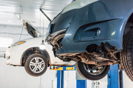 Damaged car bumper and undercarriage on hydraulic lift for automotive repair, inspection and garage service.