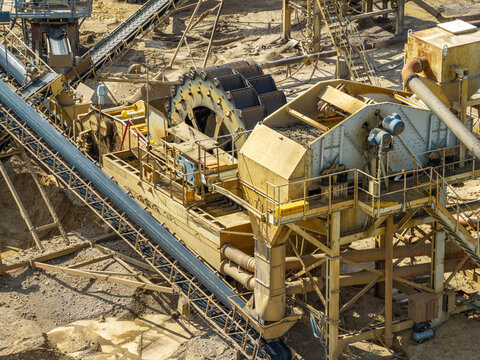 Aerial view of a sand and gravel quarry featuring industrial conveyor belts and a large washing wheel for material processing in Poland.