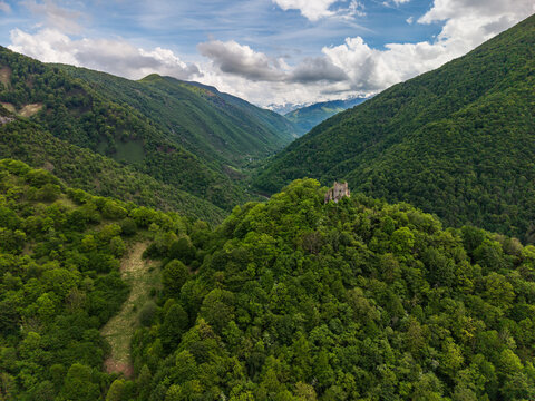 Aerial view of the ruins of Chateau de la Garde situated on a forested hill overlooking the confluence of the Le Salat and LAlet rivers in the Pyrenees mountains, Seix, Occitanie, France.