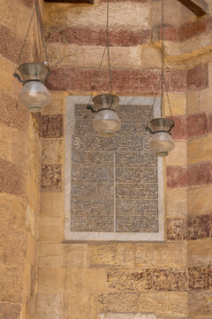View of Arabic calligraphy on a marble panel at the Aqsunqur Mosque, with hanging glass lamps and traditional ablak masonry in El-Darb El-Ahmar, Cairo Governorate, Egypt.