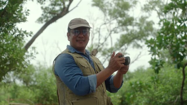 Happy active senior man walking through a forest taking photos of nature after retirement. Active aging outdoor recreation, healthy longevity, retirement lifestyle. Life insurance. Joyful living.
