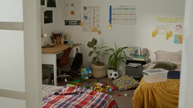 Empty child bedroom displaying scattered toys on floor, unmade bed, and study desk. Footage is suitable for parenting blogs, home organization services, or family lifestyle advertisements