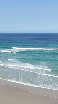 Vertical 9:16 video showing gentle waves rolling onto the sandy shore at Praia do Rostro, Spain.