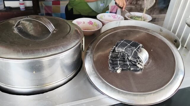 Street Food Vendor Cutting Noodles with Scissors over Steaming Cooking Pots at Indonesian Mie Ayam Stall Concept of Asian Cuisine
