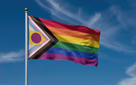 Progress Pride flag waving on flagpole. Inclusive LGBTQ+ rainbow flag against blue sky. Intersex-inclusive pride banner for community events.