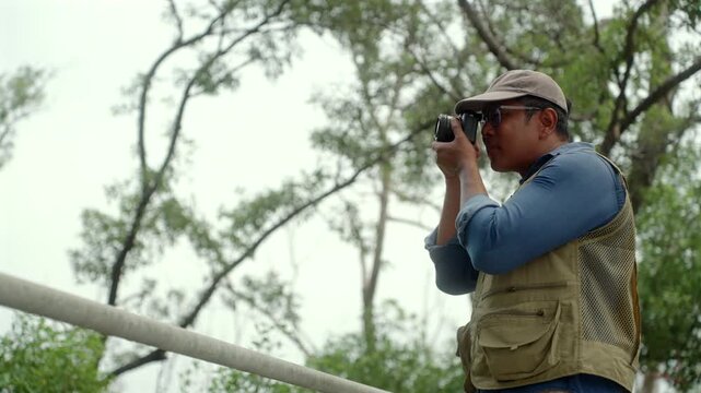 Experienced senior male photographer capturing the beauty of nature in a forest. Active aging creative retirement, outdoor photography, lifelong passion, healthy longevity and fulfilling lifestyle.
