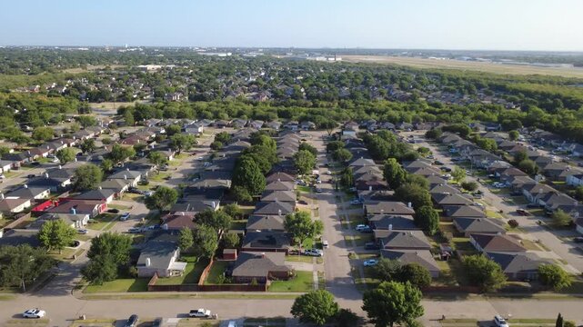 Dark rooftop shingles define single family lots along Nicole Court neighborhood tracts. Tidy fenced lawns border wide paved community streets, leafy green tree canopies, Arlington, Texas