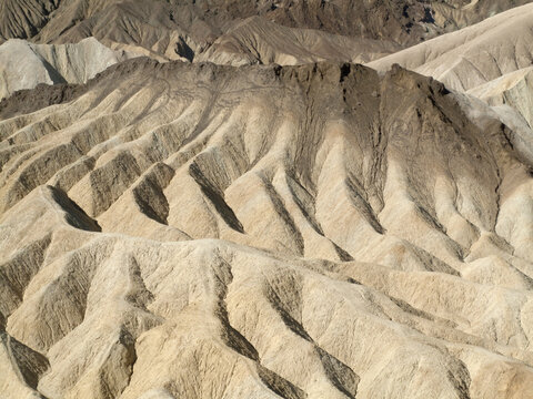 View of the golden eroded badlands and sharp ridges of Zabriskie Point in Death Valley, California, United States.