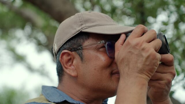 Experienced senior male photographer capturing the beauty of nature in a forest. Active aging creative retirement, outdoor photography, lifelong passion, healthy longevity and fulfilling lifestyle.
