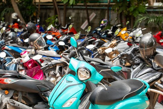 Densely packed motorcycles and scooters parked closely together in outdoor parking area, urban transportation concept